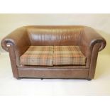 A brown leather two seater sofa with Chesterfield style scroll arms and back