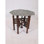 A Middle Eastern pierced and tooled copper table with well carved folding base, 25" diameter x 22"