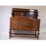 A Jacobean style oak sideboard, with inset mirror back top and two drawers flanked by cupboards with
