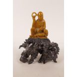 A Chinese amber soapstone carving of Lohan and a kylin, mounted on a gnarled rootwood base, 7" high