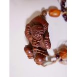A Chinese hardwood amulet carved as a traveller with a large gourd, inset with hardstone bead