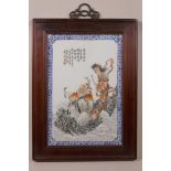 A Chinese porcelain panel decorated with two immortals in red and black robes, mounted in a hardwood