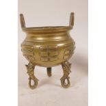 A Chinese polished bronze cauldron shaped censer with two loop handles and raised on three mask