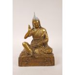 A Tibetan gilt metal figure of a Buddhist priest, inscription to front, 11" high