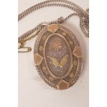 A Victorian silver locket with gold embellished floral decoration on a fine silver chain, gross 26.