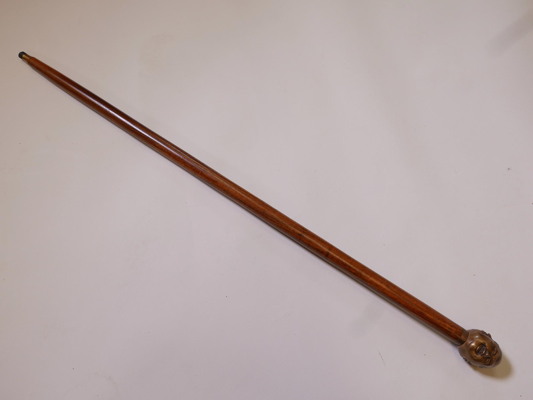 A hardwood walking stick with brass four-face Buddha head handle, 36" long