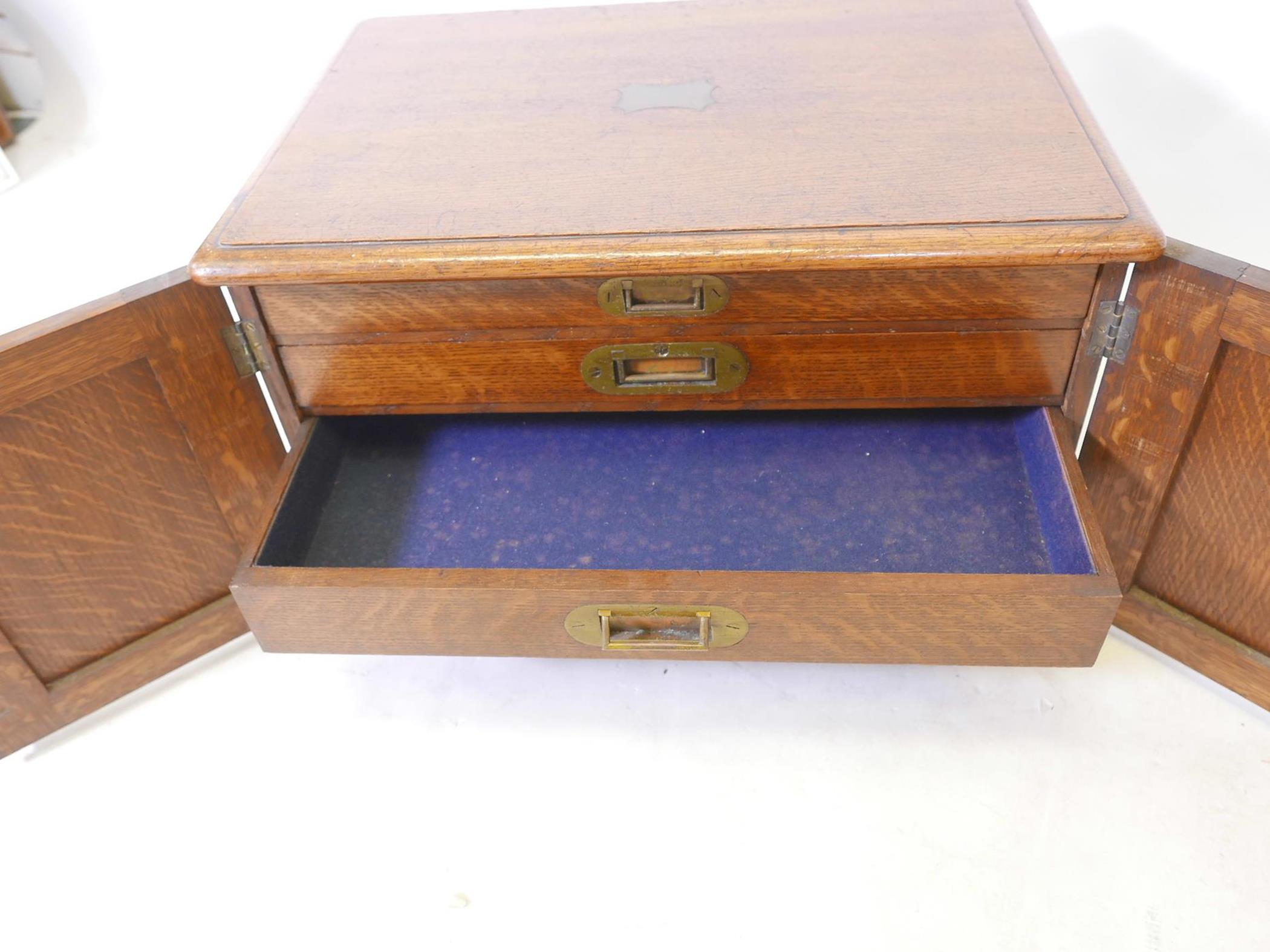 An Edwardian oak cutlery canteen with two panelled doors and brass carrying handles, concealing four - Image 3 of 4