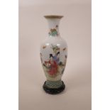A Chinese famille vert porcelain vase decorated with women and their attendants, on a carved