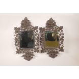 A pair of pierced bronze framed mirrors decorated with flowers, dolphins, the green man etc, 10" x