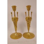 A pair of polished brass candlesticks cast with baccus heads and vines, 11" high