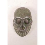 A Tibetan white metal skull with applied green patina and impressed vajra decoration, 3½" x 2"