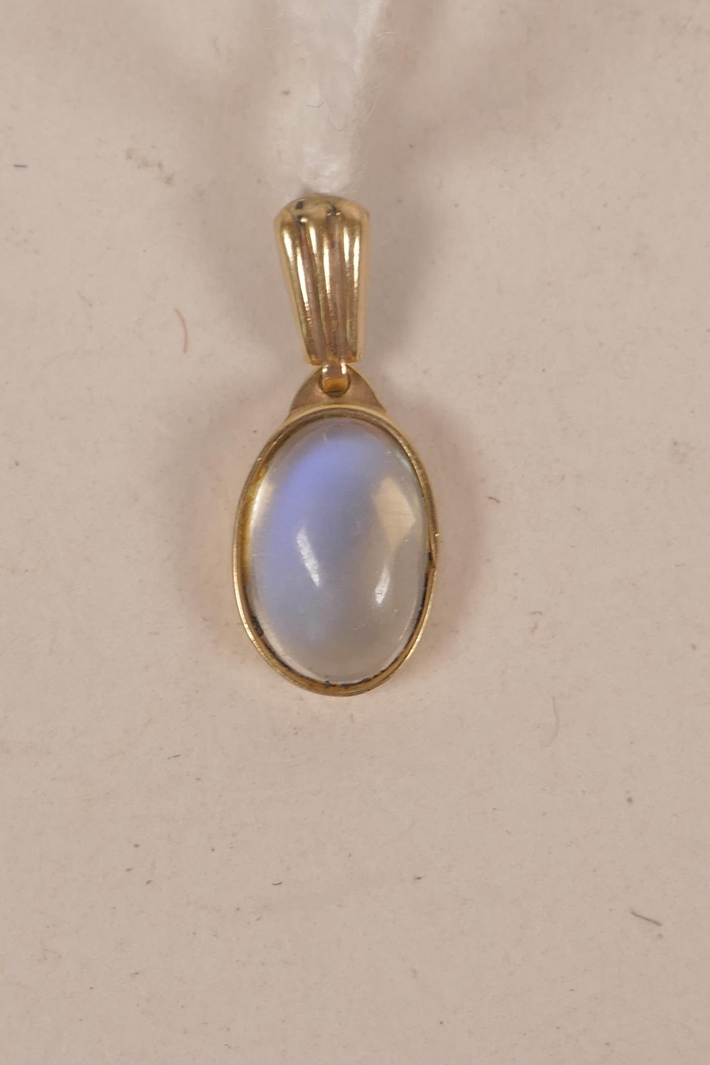 A yellow metal pendant set with a moonstone
