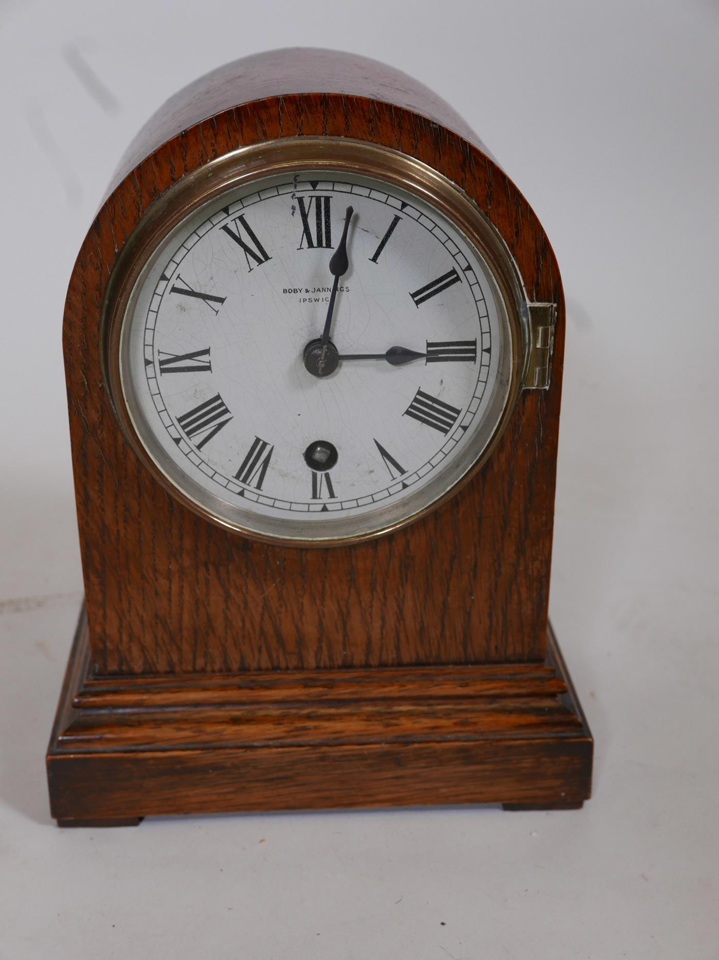 An oak cased dome top mantel clock by Bobby & Jennings of Ipswich, with silvered dial and Roman