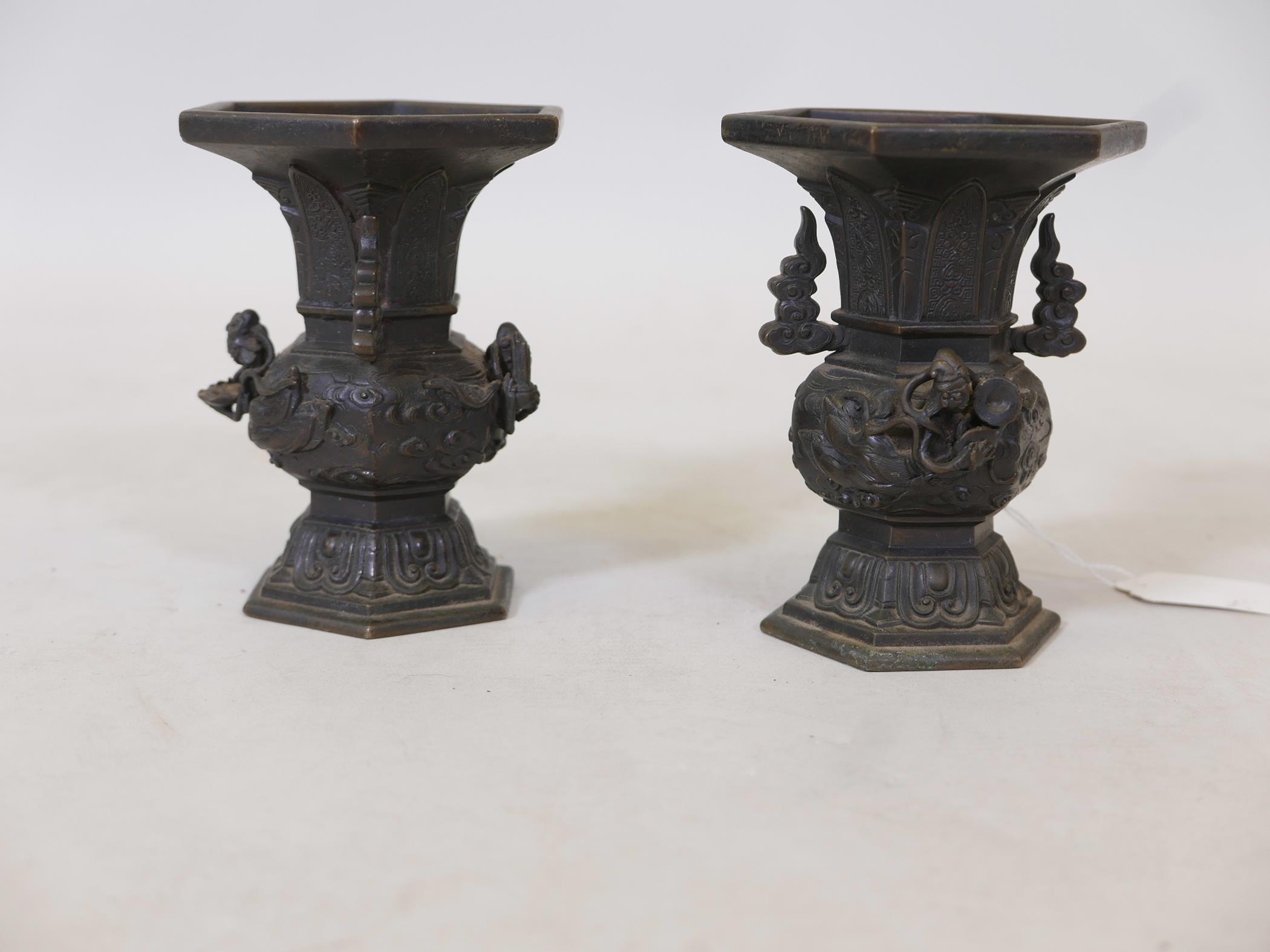 A pair of oriental bronze vases with raised decoration depicting deities flying amongst clouds,