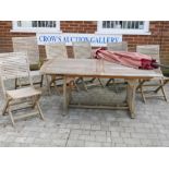 A teak garden table and six matching chairs, with a red canvas parasol, table 39" x 71"