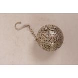 A Chinese pierced white metal ball shaped incense holder with gimball mounted reservoir to the
