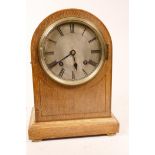 An oak cased dome top mantel clock with striking movement on a gong, the silvered dial with Roman