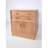 A mid century E. Gomme G-Plan teak secretaire, the top drawer fitted with pigeon holes, raised on