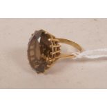 A 9ct gold and smoky quartz dress ring set with a large oval cut stone set in a cage mount, size