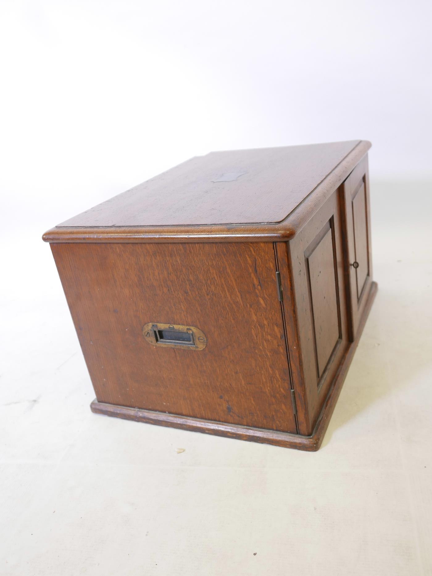 An Edwardian oak cutlery canteen with two panelled doors and brass carrying handles, concealing four - Image 4 of 4