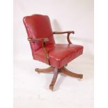 An oak framed office swivel elbow chair on brass castors upholstered in red leather bears label "