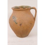 An antique red earthenware single handled jar bearing traces of a salt glaze, 7½" high
