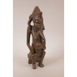 An African carved hardwood maternity figure of a mother and child, 12½" high