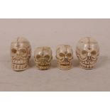 Four bone and composition beads carved in the form of skulls, 1½" largest