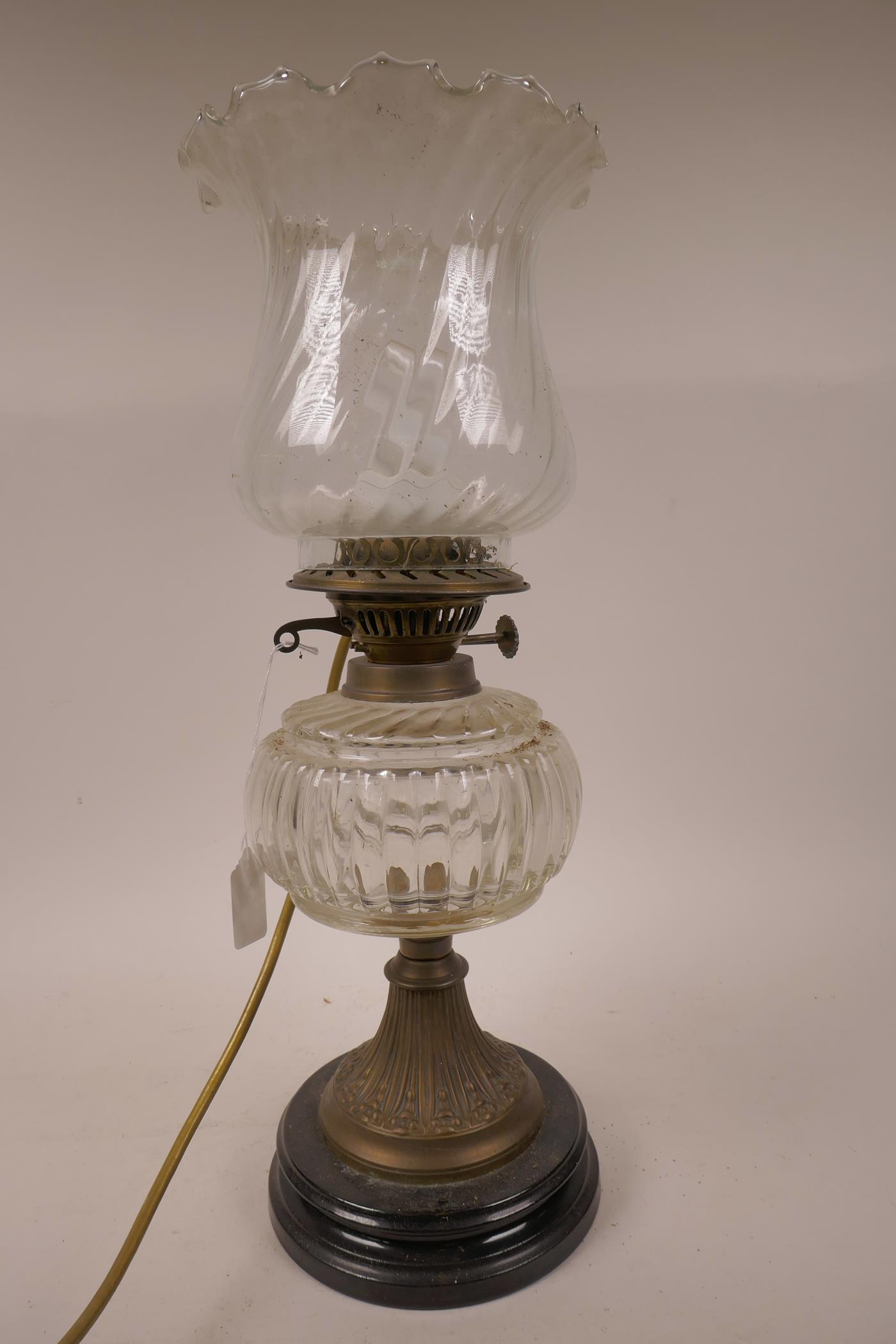 A C19th glass and brass oil lamp with glass shade and font on a classical brass and wood column