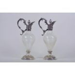 A pair of silver plate and whirled glass decanters with cast serpent handles and pineapple