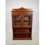 A walnut bookcase with leaded glass doors over two open shelves raised on a plinth base, 32" x 9"