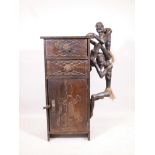 An African stinkwood cabinet with two drawers and single door, and decorated with two carved