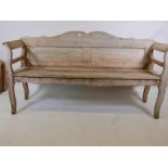 A Dutch pine hall/garden bench with shaped back and scroll arms, 72" wide, and upholstered cushion