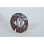 A Japanese cast iron tsuba decorated with pigs in a jungle, the animals with gold inlaid eyes,