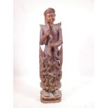 An oriental carved hardwood figure of a deity wearing a crown, standing on a lotus base, 46½" high