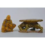 A Chinese amber soapstone carving of Lohan, on an olive glazed pottery stand, 6½" high total