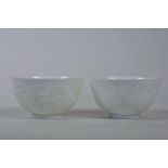 A pair of Chinese white ground porcelain tea bowls with white enamel dragon and kylin decoration,