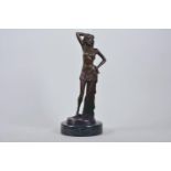 A bronze figure of a girl standing in an artistic pose, marked Nöll, on a round marble stand, 12"