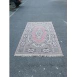 A Belgian salmon pink ground wool carpet, decorated with a floral medallion, 78" x 118"