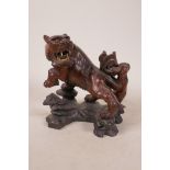 A Chinese carved hardwood tiger with ivory teeth and glass set eyes, 7½" high