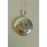 A silver pendant locket, the front with applied cast silver owl's head with stone set eyes