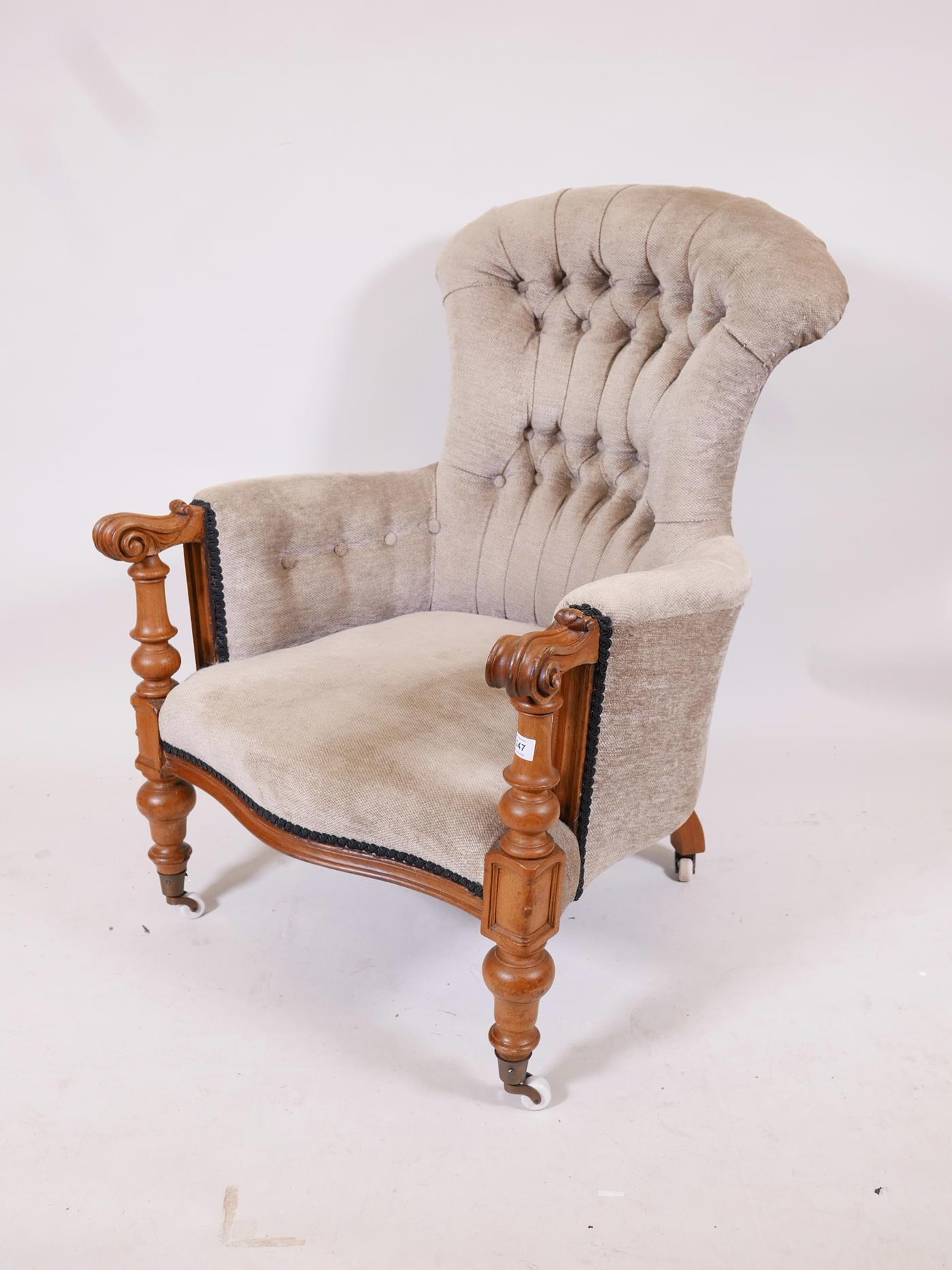 A C19th walnut show frame armchair with scrolled arms and serpentine front, raised on turned