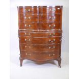 A mahogany serpentine fronted tallboy, with canted corners and carved decoration, raised on sabre