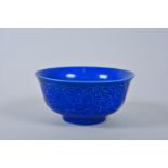 A Chinese blue glazed porcelain rice bowl with raised decoration of dragons in flight, 6"