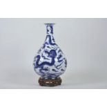A Chinese blue and white porcelain pear shaped vase with dragon decoration, on a carved and