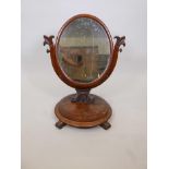 A Victorian mahogany swing toilet mirror with oval plate in yoke support, on a round platform base