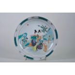 A Chinese famille verte porcelain charger decorated with women and children playing musical