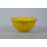 A Chinese yellow glazed porcelain rice bowl with raised decoration of a dragon and phoenix chasing