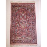 A Persian red round wool rug with floral and bird decoration, possibly retailed by Bloomingdales,