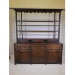 A C19th oak dresser with three frieze and two central drawers flanked by cupboards with brass drop